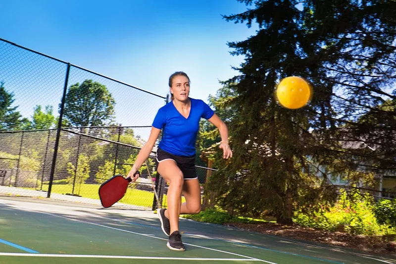 woman hitting a pickleball